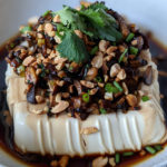 Steamed tofu topped with mushrooms, peanuts and soy sauce.